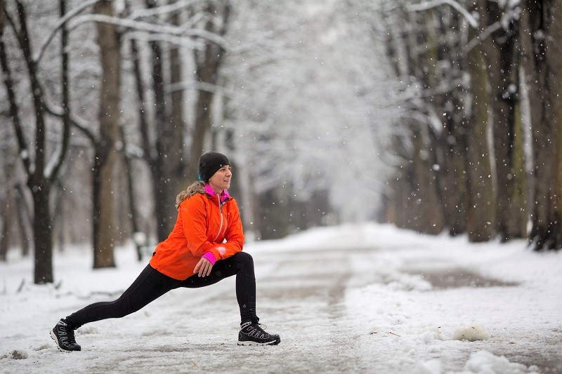 a person stretching outside on a cold winters day