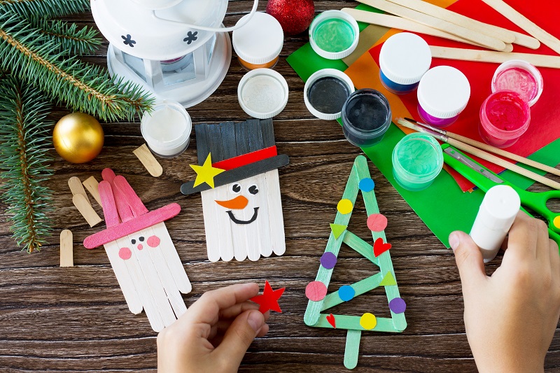 kid making holiday crafts. family reading a book at Christmas. holiday activities