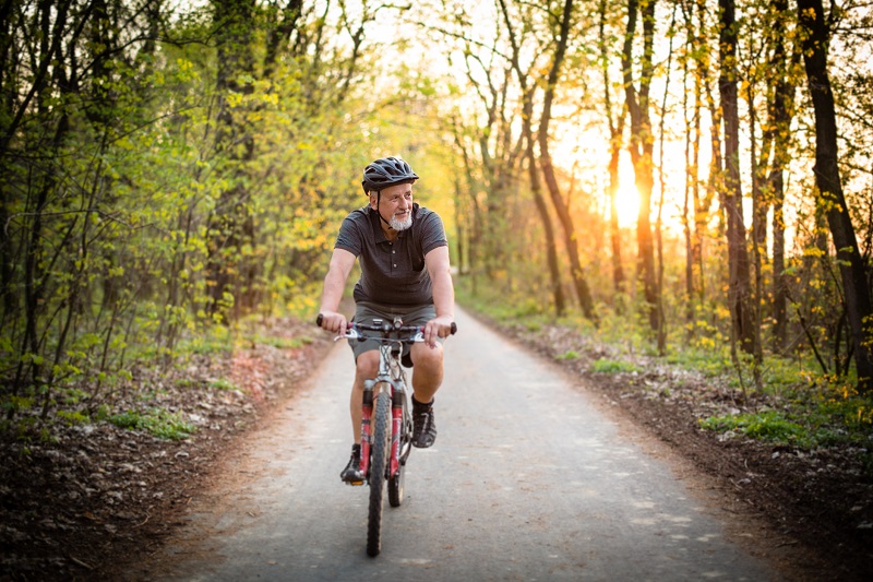 an elderly man cycling in a park