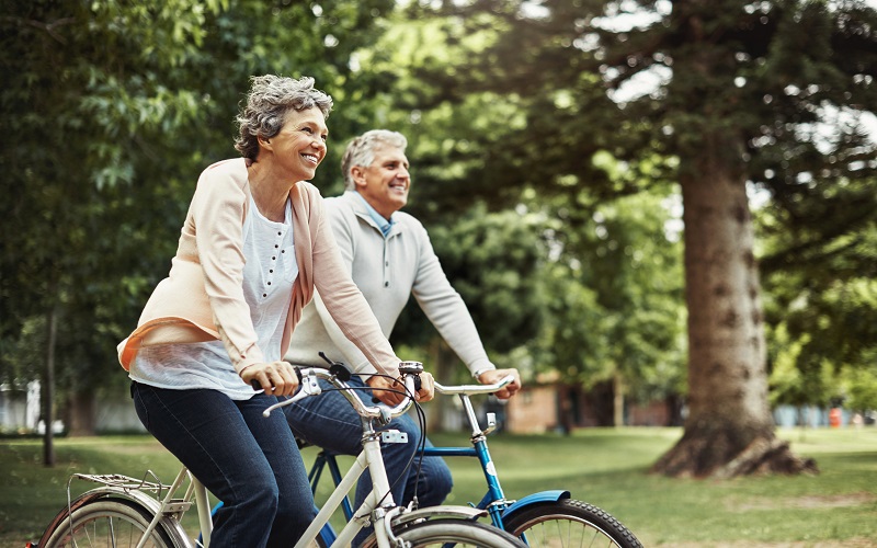 an elderly couple cycling in a park